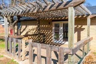 view of home's exterior featuring brick siding, a pergola, and french doors