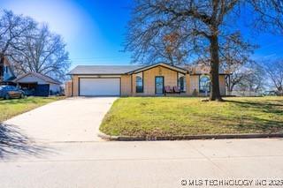 view of front of property featuring an attached garage, a front lawn, and concrete driveway