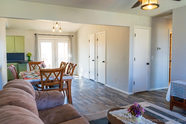 living area with a textured ceiling, wood finished floors, visible vents, and baseboards