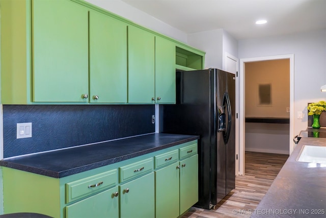 kitchen featuring tasteful backsplash, recessed lighting, black refrigerator with ice dispenser, a sink, and wood finished floors