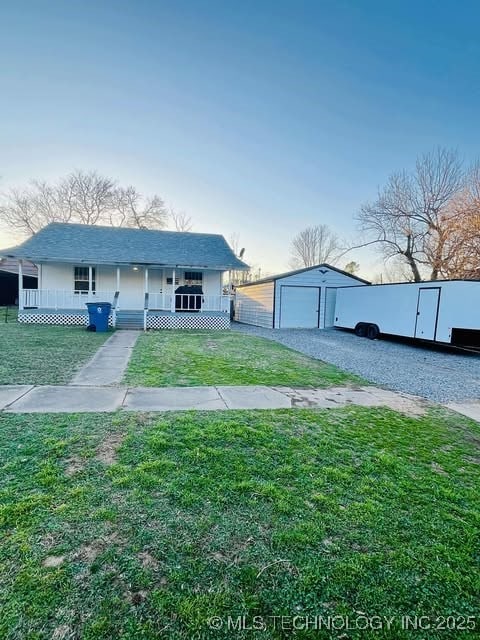 view of front facade featuring covered porch, a front lawn, an outdoor structure, and gravel driveway