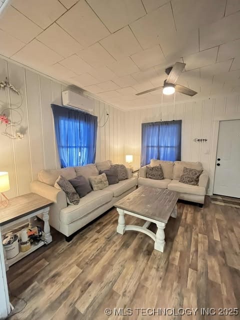 living area featuring an AC wall unit, ceiling fan, and wood finished floors