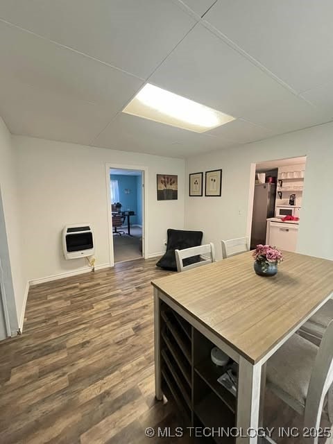 dining space with heating unit, baseboards, and wood finished floors