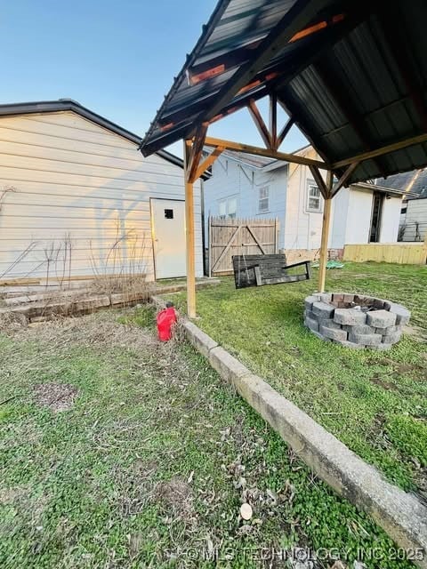 view of yard with an outdoor fire pit and fence