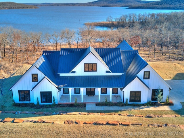 modern inspired farmhouse featuring a water view, a standing seam roof, metal roof, and board and batten siding