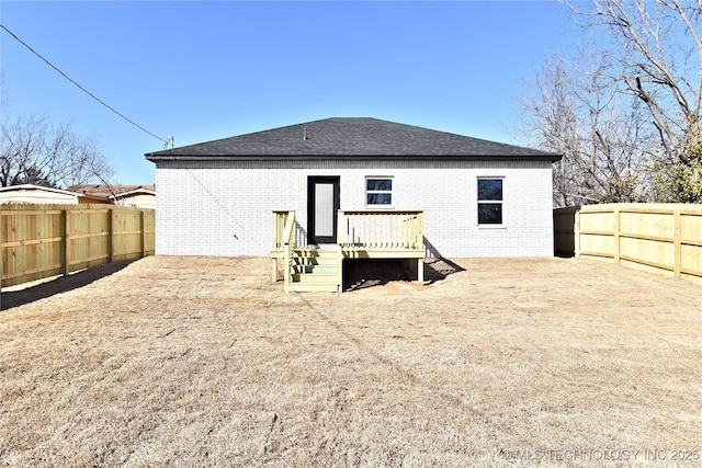 back of house featuring brick siding, roof with shingles, a fenced backyard, and a wooden deck