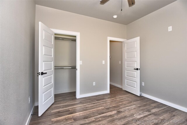 unfurnished bedroom featuring dark wood-style floors, a ceiling fan, baseboards, and a closet