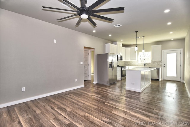 kitchen with a center island, stainless steel appliances, visible vents, backsplash, and dark wood-type flooring