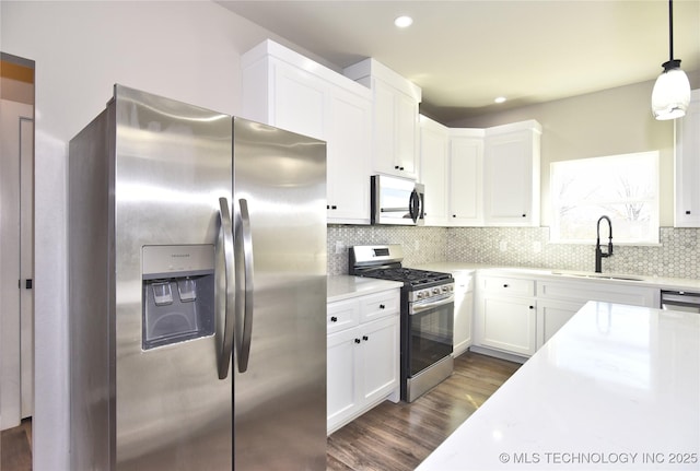 kitchen with stainless steel appliances, light countertops, a sink, and decorative backsplash