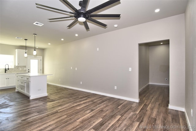 interior space with a center island, visible vents, dark wood-type flooring, white cabinetry, and a sink