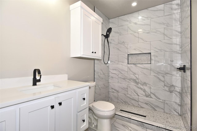 full bath with marble finish floor, tiled shower, vanity, and toilet