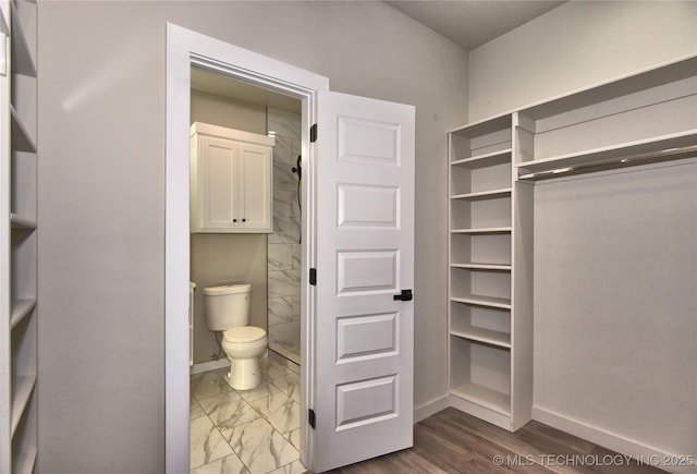 bathroom with toilet, marble finish floor, baseboards, and walk in shower