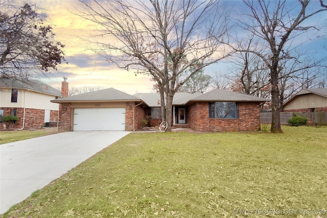 ranch-style home with a garage, a front yard, concrete driveway, and brick siding