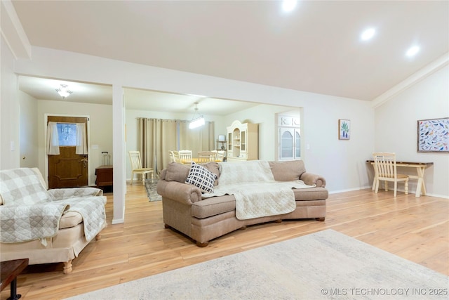 living room featuring vaulted ceiling, light wood-style flooring, and baseboards