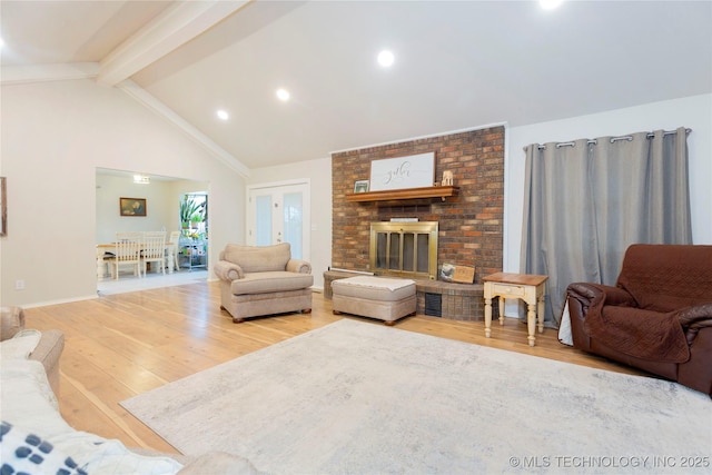 living area featuring baseboards, beamed ceiling, wood finished floors, a brick fireplace, and recessed lighting