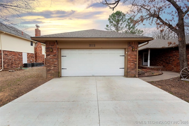 exterior space featuring driveway, a shingled roof, an attached garage, central AC, and brick siding