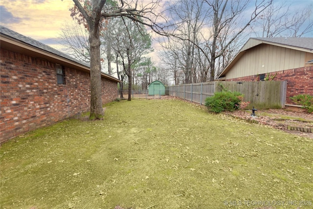 yard at dusk with a fenced backyard and an outdoor structure