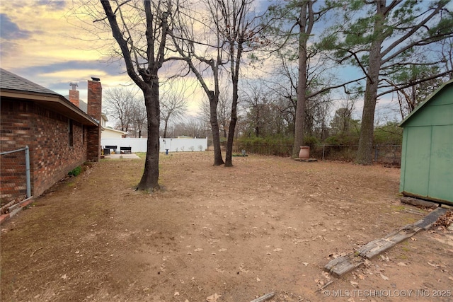 yard at dusk with an outbuilding, a storage unit, and fence