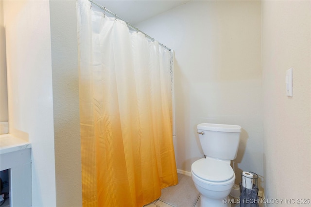 bathroom with toilet, tile patterned flooring, and baseboards