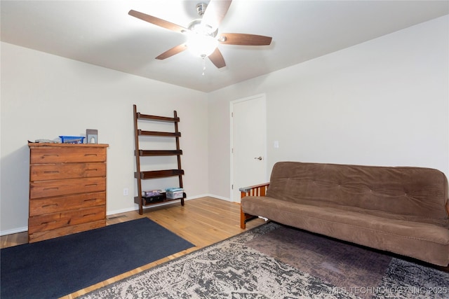 sitting room with wood finished floors, a ceiling fan, and baseboards