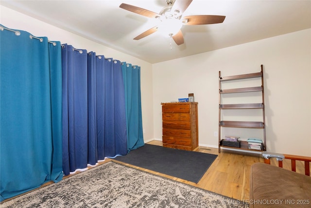 interior space featuring wood finished floors, a ceiling fan, and baseboards