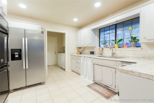 kitchen featuring a sink, washing machine and dryer, white cabinetry, and stainless steel fridge with ice dispenser