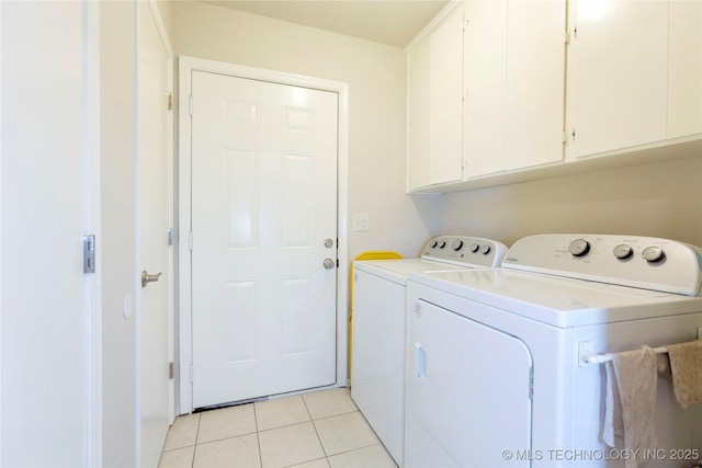 washroom with light tile patterned flooring, washing machine and dryer, and cabinet space