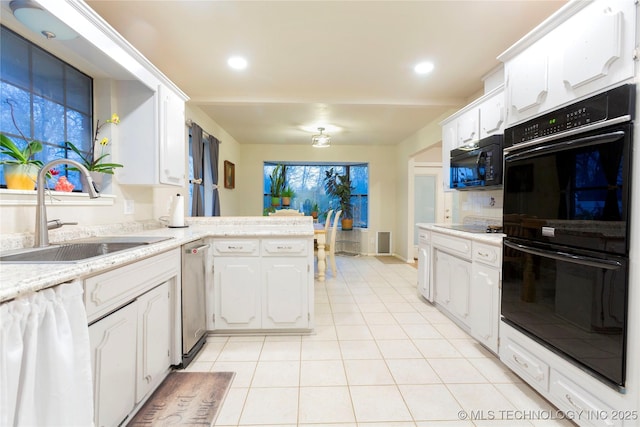 kitchen with light tile patterned floors, a peninsula, a sink, white cabinets, and black appliances