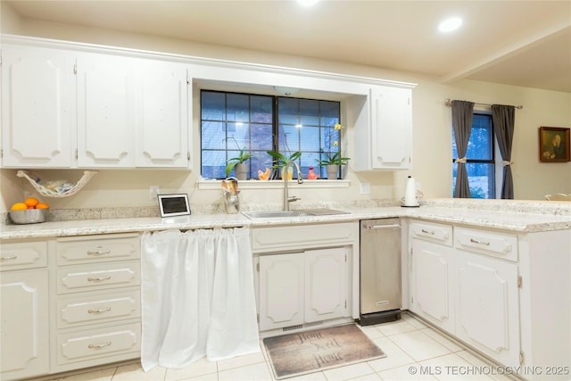 kitchen with a peninsula, light tile patterned floors, white cabinetry, and a sink