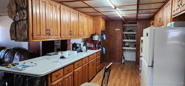 kitchen featuring light wood-style flooring, brown cabinets, light countertops, and freestanding refrigerator