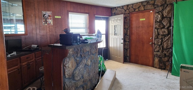 carpeted office space with a textured ceiling and wooden walls