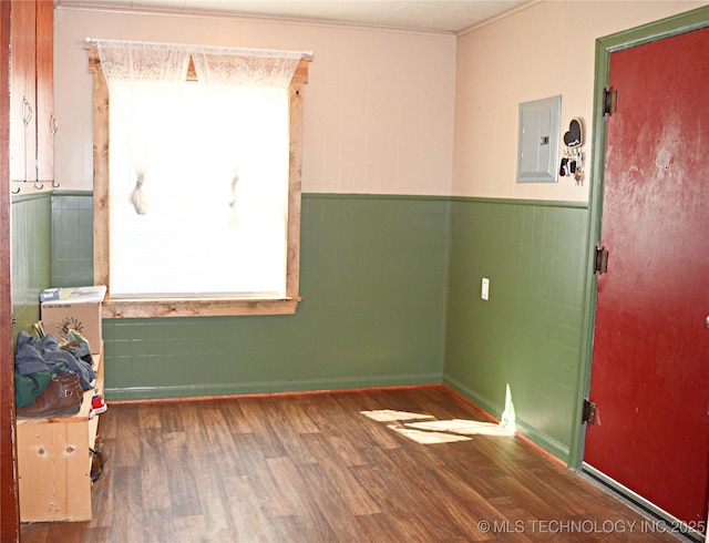 empty room featuring a wainscoted wall, electric panel, crown molding, and wood finished floors