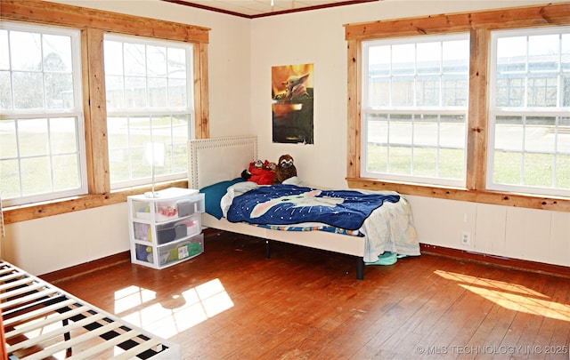 bedroom featuring crown molding, hardwood / wood-style floors, and baseboards