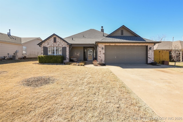 view of front facade with roof with shingles, concrete driveway, an attached garage, a front yard, and cooling unit