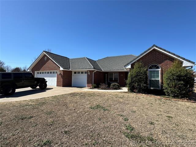 single story home featuring a garage, a front yard, brick siding, and driveway