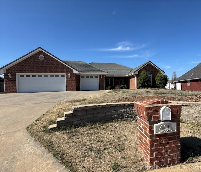 ranch-style home with brick siding, an attached garage, driveway, and a tile roof