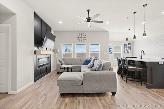 living area with light wood finished floors, ceiling fan, baseboards, and recessed lighting