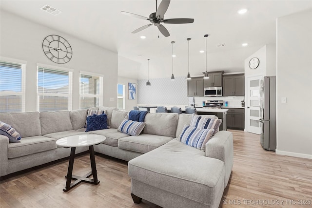 living room with light wood-style flooring, a high ceiling, visible vents, and recessed lighting