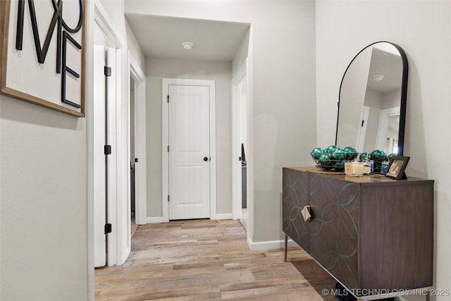 hall featuring light wood finished floors and baseboards