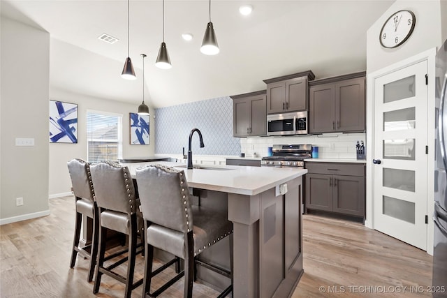 kitchen with a sink, visible vents, light countertops, appliances with stainless steel finishes, and an island with sink