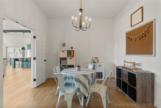 dining space with baseboards, light wood-style flooring, and an inviting chandelier