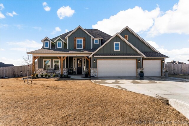 craftsman inspired home with a shingled roof, covered porch, concrete driveway, fence, and stone siding