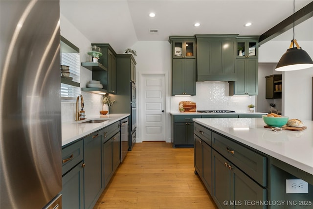 kitchen featuring freestanding refrigerator, a sink, green cabinets, and open shelves