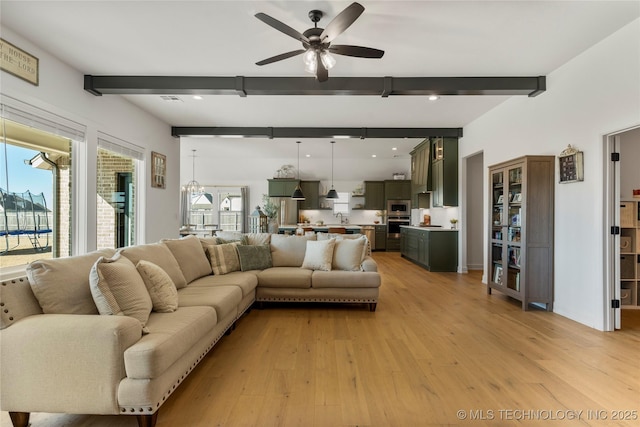 living area featuring light wood finished floors, beamed ceiling, and plenty of natural light