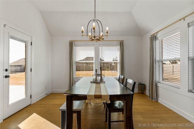 dining room with an inviting chandelier, lofted ceiling, baseboards, and light wood-style flooring