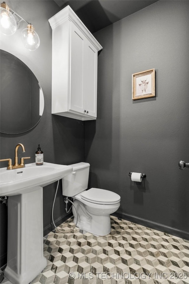 half bath featuring toilet and baseboards