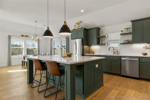 kitchen with open shelves, light countertops, a sink, green cabinets, and stainless steel appliances