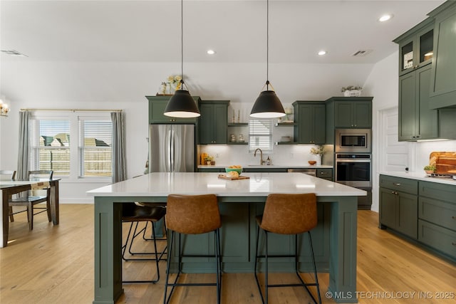 kitchen featuring backsplash, appliances with stainless steel finishes, open shelves, a sink, and green cabinetry