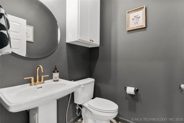 bathroom featuring a textured wall, a sink, and toilet