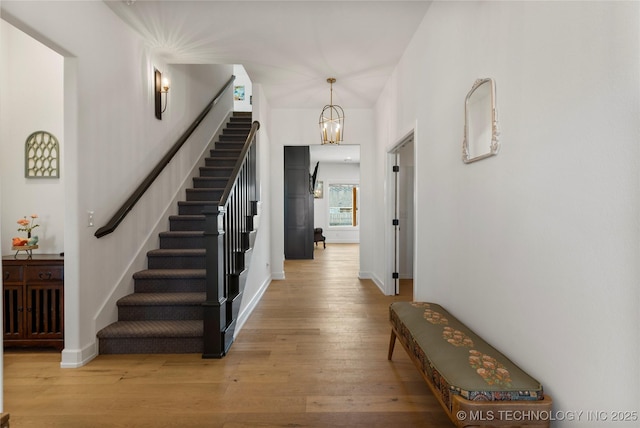 foyer featuring light wood-style floors, stairs, baseboards, and an inviting chandelier